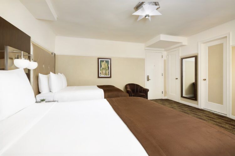 A hotel room with a double bed, chair, and doorway.