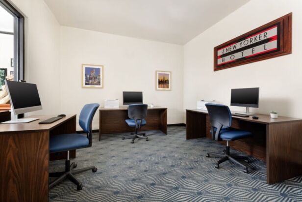 A meeting room with four desks, four chairs, and three computers.