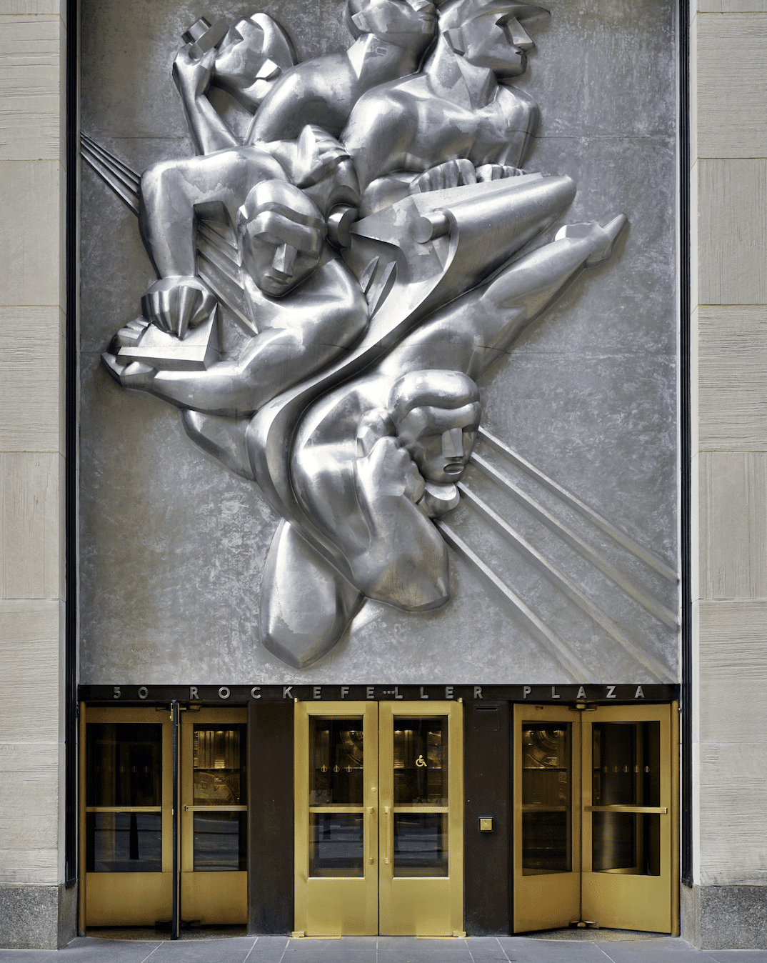A large metal sculpture above a set of golden doors